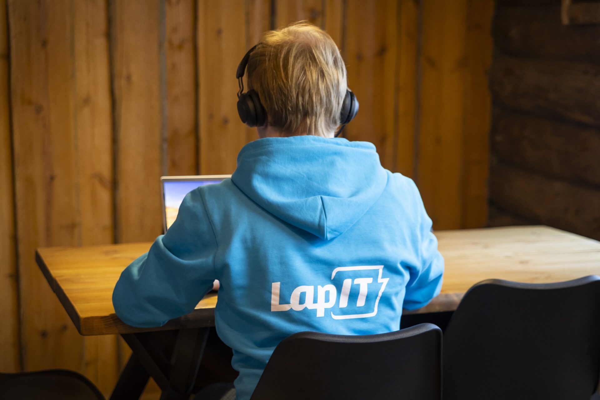 LapIT asiantuntija etätöissä kannettavan äärellä ja kuulokkeet päässä.